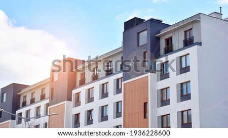 Futuristic square architecture of apartment building. Real estate with panoramic windows and blue sky with clouds.