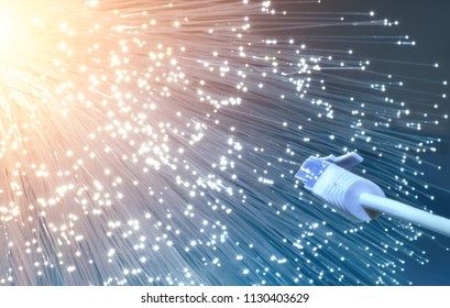 Futuristic technological background, closeup on the end of optical fiber network cable on blue-orange background