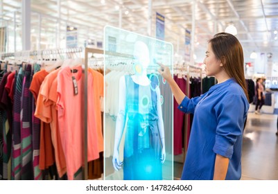futuristic technology concept.happy girl try to use smart hologram display with virtual augmented reality in the shop or retail to choose select ,buy clothes and change a color of products.