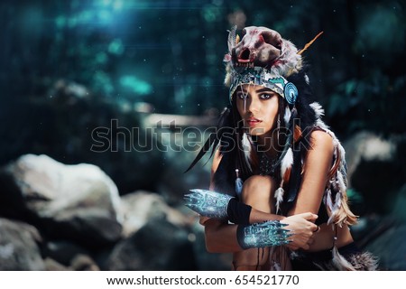 Futuristic tribal indian woman portrait with wolf skull hat outdoors. Blue magical forest on background