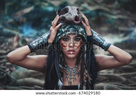 Futuristic tribal indian woman portrait with wolf skull hat outdoors. Blue magical forest on background
