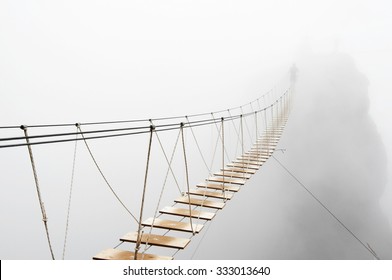 Fuzzy man walking on hanging bridge vanishing in fog. Focus on middle of bridge.  - Shutterstock ID 333013640