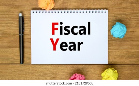 FY Fiscal year symbol. Concept words FY Fiscal year on white note. Metallic pen. Beautiful wooden background. Business and FY fiscal year concept.