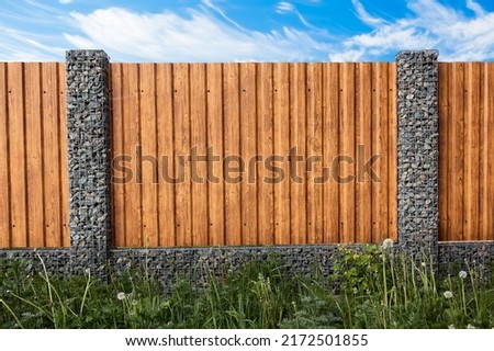 Gabion fence. Posts full of stones with sections from wooden planks. Countryside style. Exterior garden element design. Security wall. Natural materials. Isolated. Nature texture. Close-up.