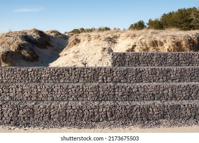 Gabion wall of metal mesh cage filled with rocks protects sand dunes - Shutterstock ID 2173675503