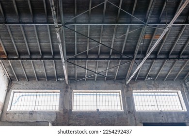Gable roof truss of a large, vintage factory hall. Roofing construction 
(sheathing) made of wooden planks. Industrial interior. - Shutterstock ID 2254292437