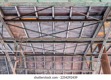 Gable roof truss of a large, vintage factory hall. Roofing construction 
(sheathing) made of wooden planks. Industrial interior. - Shutterstock ID 2254292439