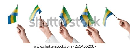 The Gabon flag in hand in different angles on a white background