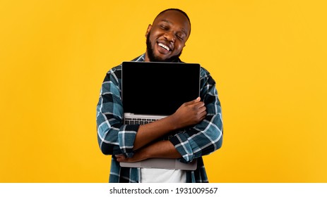 Gadget Lover. Happy African Man Hugging Laptop Computer With Blank Screen Standing Posing Over Yellow Studio Background. Great Website Advertisement. Panorama, Mockup