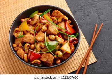 Gai Pad Med Mamuang or Thai Cashew Chicken in black bowl on dark slate backdrop. Kai Med Ma Muang is thai cuisine dish with chicken meat, capsicum, onion, scallions, chilli. Thai Food - Shutterstock ID 1723667680