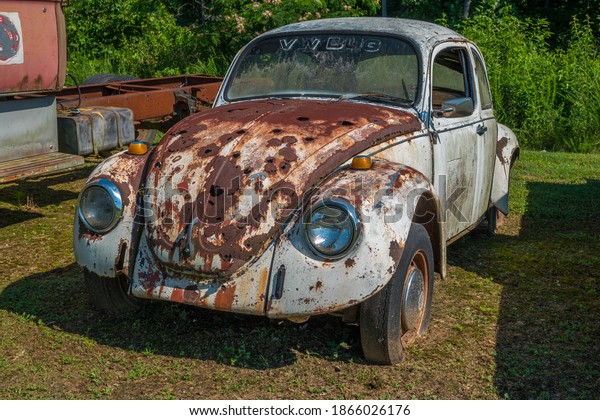 Gainesville, Georgia, USA\
- June 13, 2020  VW bug rusting away with many holes in the hood\
discarded and abandoned in a field dirty and weathered outdoors on\
a sunny day\
closeup