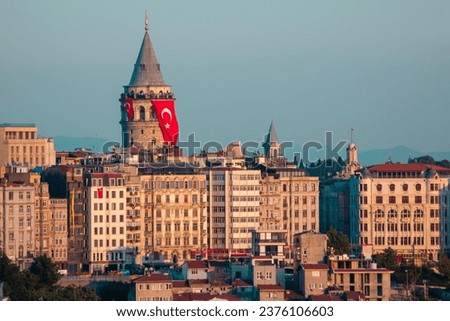 Galata Tower is located in the Beyoğlu district of Istanbul. As the sun sets, its lights reflect on the Galata tower and buildings. The Turkish flag hanging on the Galata Tower. Istanbul, Turkey.