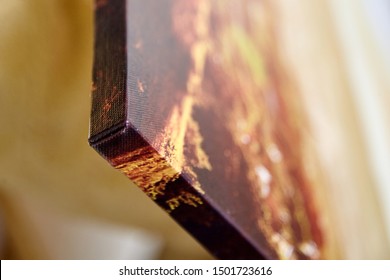 Gallery wrap canvas print without decor frame. Photo printed on a glossy cotton canvas on blurred background. Corner of photography stretched on stretcher bar, lateral side, closeup, selective focus