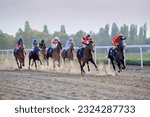 Galloping race horses and jockeys racing towards the finish line. Horse racing on sunset