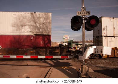GALLUP, NEW MEXICO - DECEMBER 18, 2013: BNSF train crosses Second St, at the railroad crossing  Route 66 in downtown. Across the tracks is Alpine Lumber.