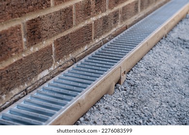 Galvanised steel channel drain installation around a conservatory wall during hard landscaping