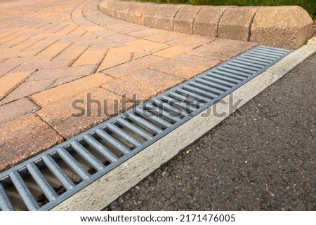 Galvanised steel drainage channel in a red block paved residential driveway