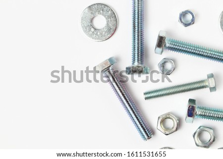 Galvanized bolts and nuts on a white background, close-up, place for text.