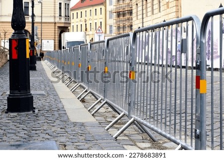 galvanized steel barricade and temporary fence of connected frame elements in a downtown street of Budapest in the castle district around the prime minister's office. cobblestone finish. construction.
