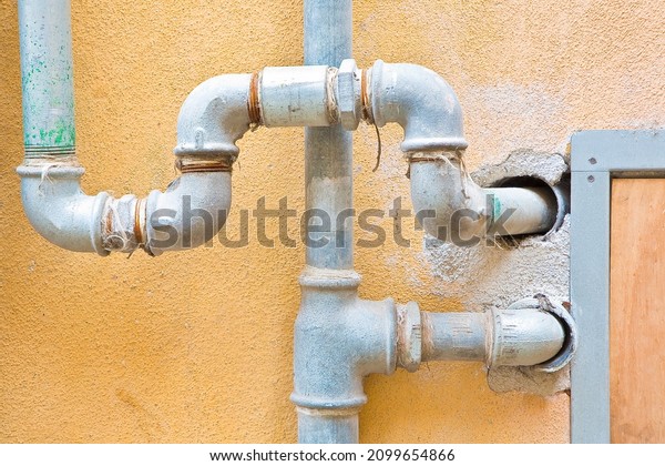 Galvanized steel\
metal pipes for water plumbing fixed to a brick and plaster wall\
with metal box for water meter\
