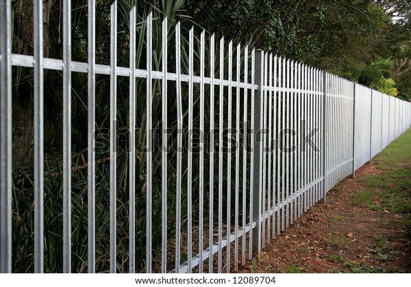 Galvanized steel palisade fence on the border of\
a property