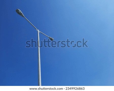 Galvanized street lighting pole against beautiful blue sky with no clouds.