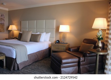 GALVESTON, TEXAS, USA –August 9: Elegant high-rise hotel guestroom suite with bed, nightstand, and upholstered armchair with ottoman by window at the San Luis in Galveston, Texas on August 9, 2015.

