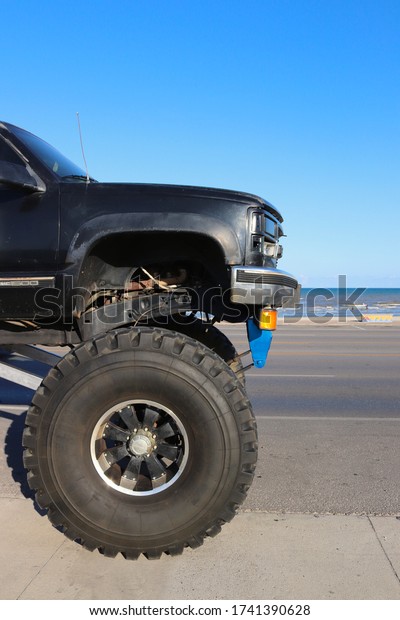GALVESTON, TEXAS, USA - JUNE 9,\
2018: A giant monster truck is parked on the street next to the\
ocean.