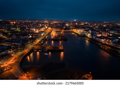 Galway city illuminated at night, The Claddagh area. Aerial high point view. Dark scene. Town at night. Popular travel destination. Business and educational center. City lights glow in the dark.