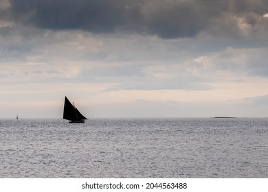 Galway hooker type wooden boat sailing in Galway bay. Cloudy sky. Calm ocean surface. Traditional local area trade fast vessel. Hobby and sport concept. Nature background