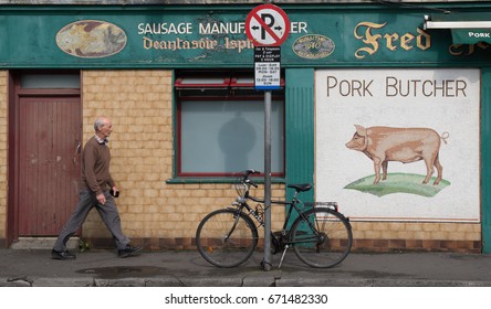 GALWAY, IRELAND - JUNE 21, 2017: A Man Walking By An Old Traditional Pork Butcher Shop In Galway City, Ireland