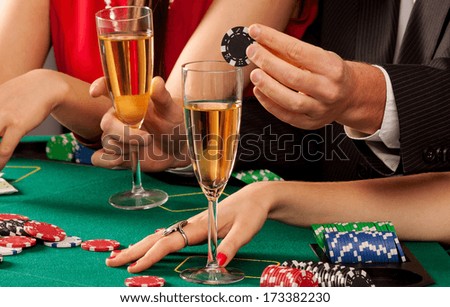 Gamblers holding casino chips and glasses of champagne