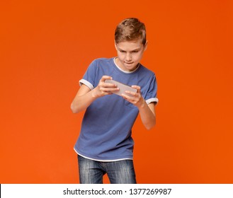 Gambling Addiction. Focused Teenage Boy Playing Video Games On Cell Phone, White Studio Background