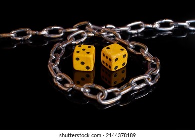 Gambling addiction. Two dice wrapped in a chain on a black background with reflection. Selective focus - Shutterstock ID 2144378189