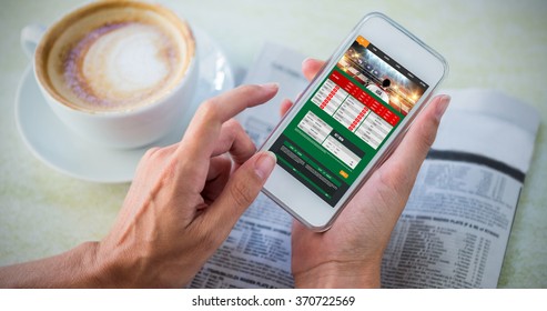 Gambling App Screen Against Man Using Mobile Phone By Coffee And Newspaper In Cafe