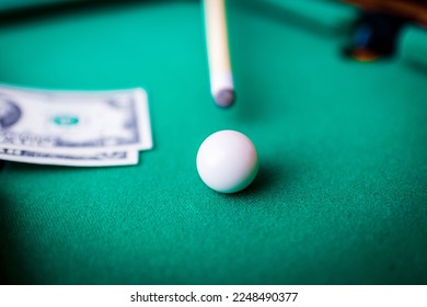 Gambling ardor game.Dollar cash and white billiard ball.Dollar paper banknotes on the game table.Selective focus. - Shutterstock ID 2248490377