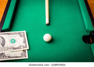 Gambling ardor game.Dollar cash and white billiard ball.Dollar paper banknotes on the game table.Selective focus. - Shutterstock ID 2248929601