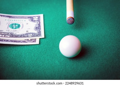 Gambling ardor game.Dollar cash and white billiard ball.Dollar paper banknotes on the game table.Selective focus. - Shutterstock ID 2248929631