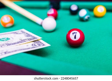 Gambling ardor game.Money and multicolored billiard balls with numbers.Dollar paper banknotes on the game table.Selective focus. - Shutterstock ID 2248045657