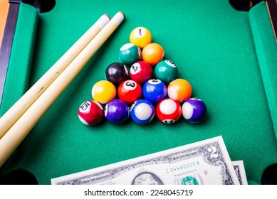 Gambling ardor game.Money and multicolored billiard balls with numbers.Dollar paper banknotes on the game table.Selective focus. - Shutterstock ID 2248045719