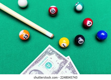 Gambling ardor game.Money and multicolored billiard balls with numbers.Dollar paper banknotes on the game table.Selective focus.Top view. - Shutterstock ID 2248045743