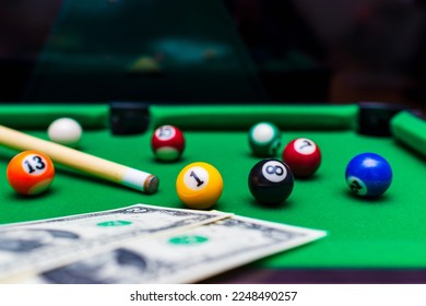 Gambling ardor game.Money and multicolored billiard balls with numbers.Dollar paper banknotes on the game table.Selective focus.Blurred background. - Shutterstock ID 2248490257