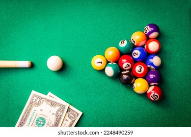 Gambling ardor game.Money and multicolored billiard balls with numbers.Dollar paper banknotes on the game table.Selective focus.Top view. - Shutterstock ID 2248490259