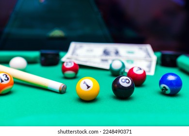 Gambling ardor game.Money and multicolored billiard balls with numbers.Dollar paper banknotes on the game table.Selective focus.Blurred background. - Shutterstock ID 2248490371