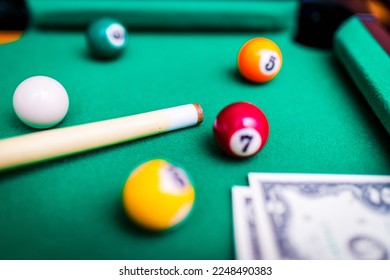 Gambling ardor game.Money and multicolored billiard balls with numbers.Dollar paper banknotes on the game table.Selective focus. - Shutterstock ID 2248490383