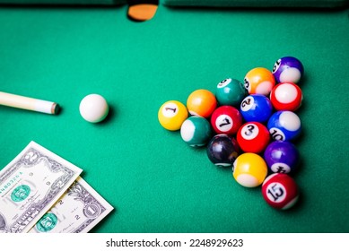 Gambling ardor game.Money and multicolored billiard balls with numbers.Dollar paper banknotes on the game table.Selective focus. - Shutterstock ID 2248929623