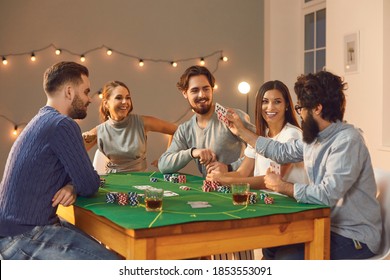 Gambling, Casino At Home, Board Games, Playing Cards Concept. Group Of Cheerful Friends Betting, Drinking And Playing Poker On Table At Home With Decorated Room Interior