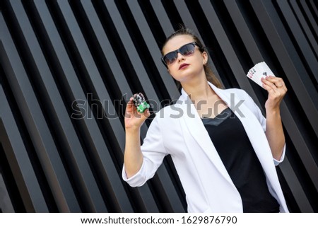 Gambling concept. Beautiful woman in white suit holding poker chips and playing cards