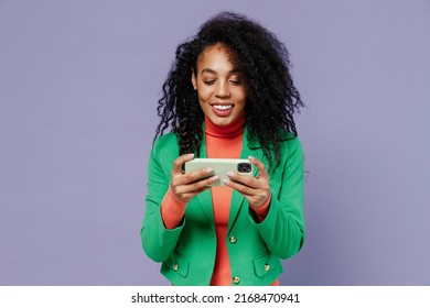 Gambling Young Black Curly Woman 20s Wears Green Shirt Using Play Racing App On Mobile Cell Phone Hold Gadget Smartphone For Pc Video Games Isolated On Plain Light Violet Background Studio Portrait