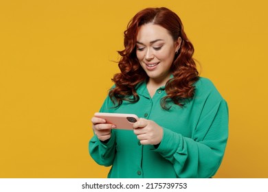 Gambling Young Ginger Chubby Overweight Woman 20s Wears Green Shirt Play Racing App On Mobile Cell Phone Hold Gadget Smartphone For Pc Video Games Isolated On Plain Yellow Background Studio Portrait